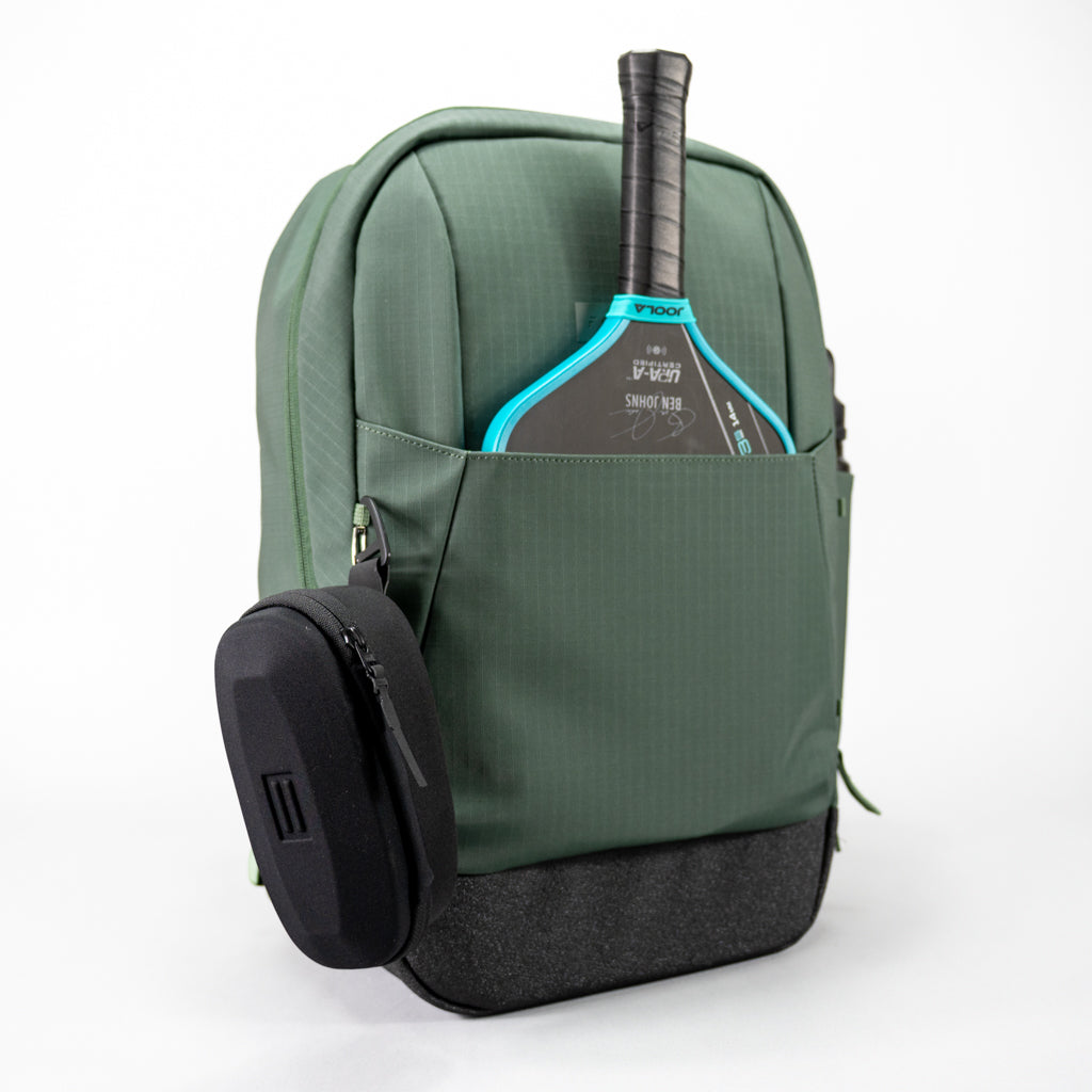 Green FORWRD Court Ranger pickleball backpack featuring a turquoise-gripped paddle in the integrated paddle sleeve front pocket and a detachable black eyewear case clipped to the side, showcasing versatile on‑court storage