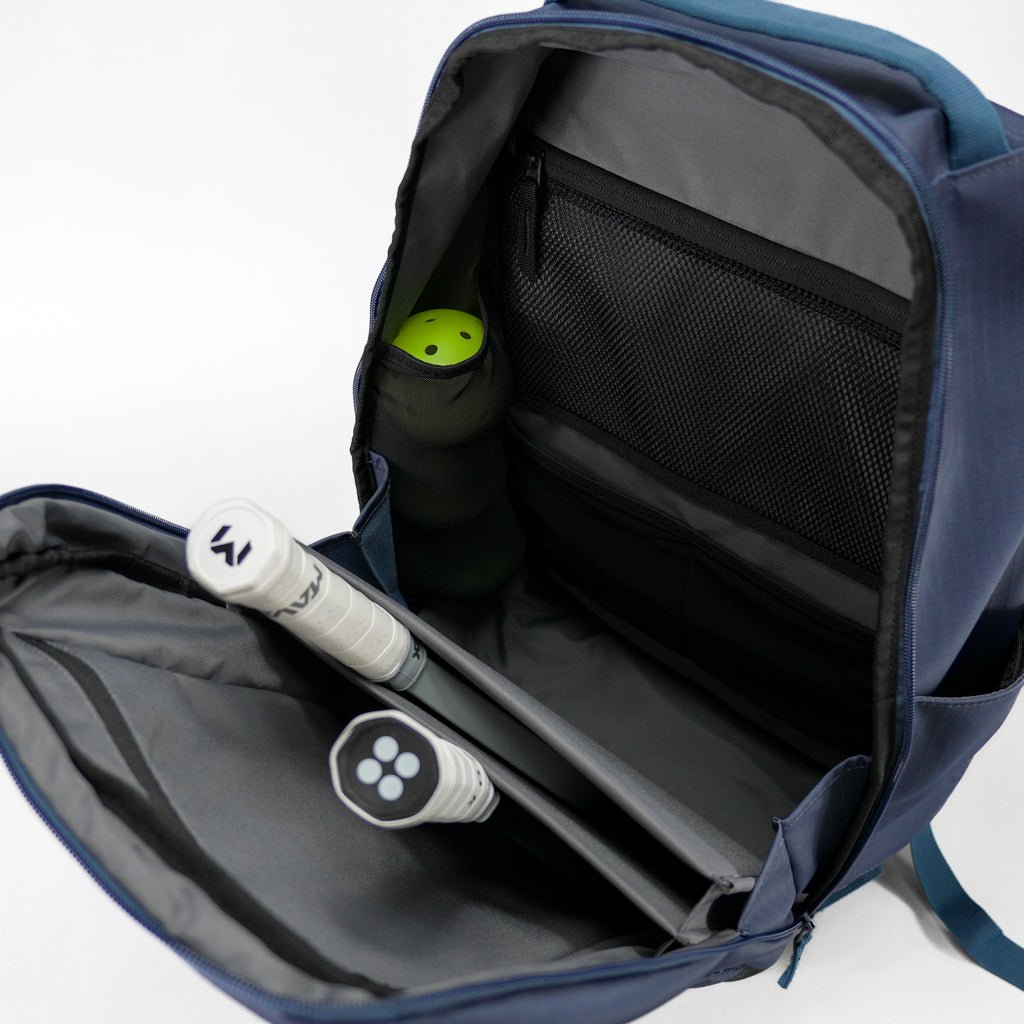 Navy blue backpack with pickleball equipment inside on a white background