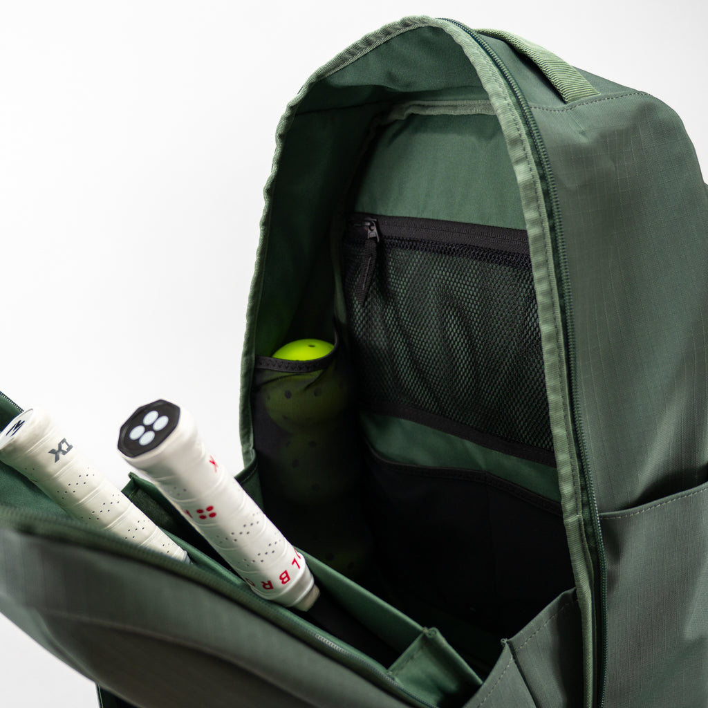Open green FORWRD Court Ranger pickleball backpack interior showing two internal paddle sleeves, a mesh zip pocket, and a side ball pocket with a bright three green pickleballs for organized on‑court storage.
