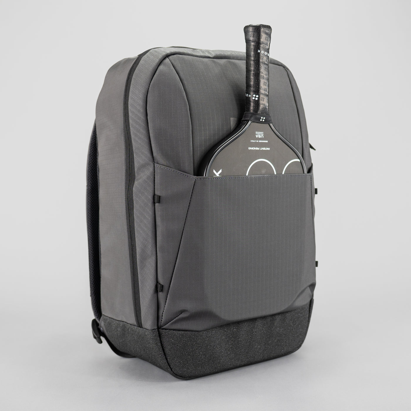 Gray backpack with a paddle in the front pocket on a light gray background