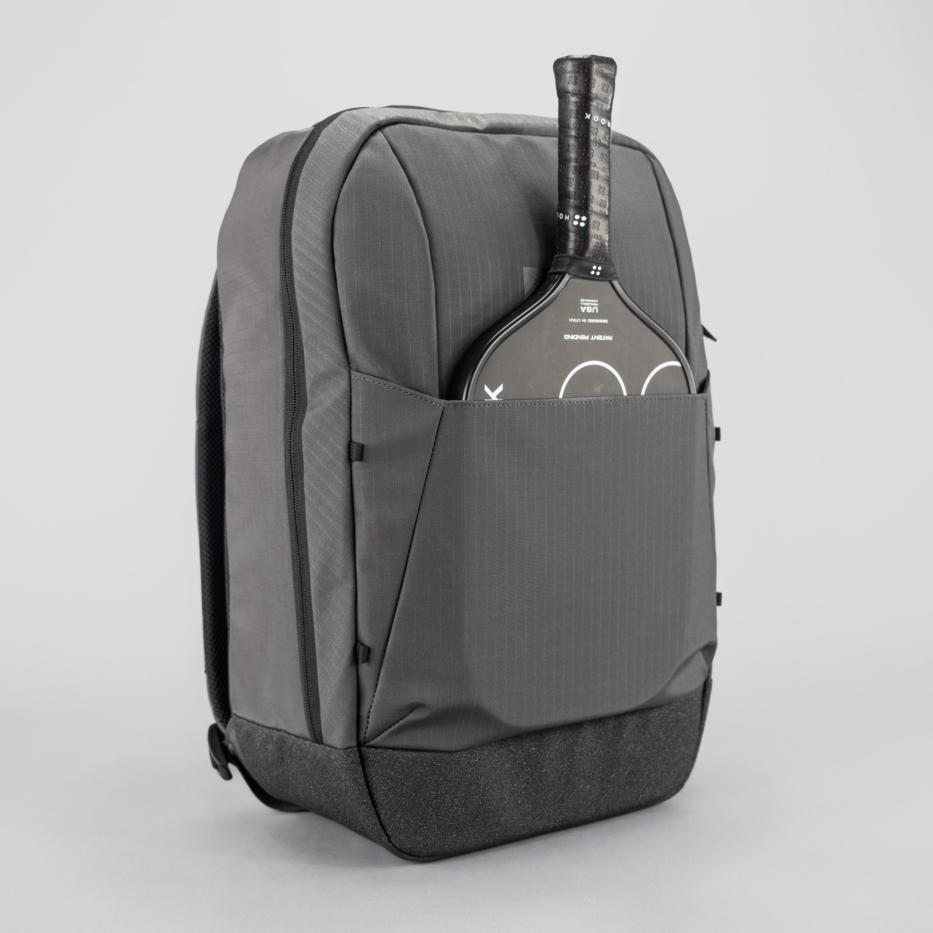 Gray backpack with a paddle in the front pocket on a light gray background