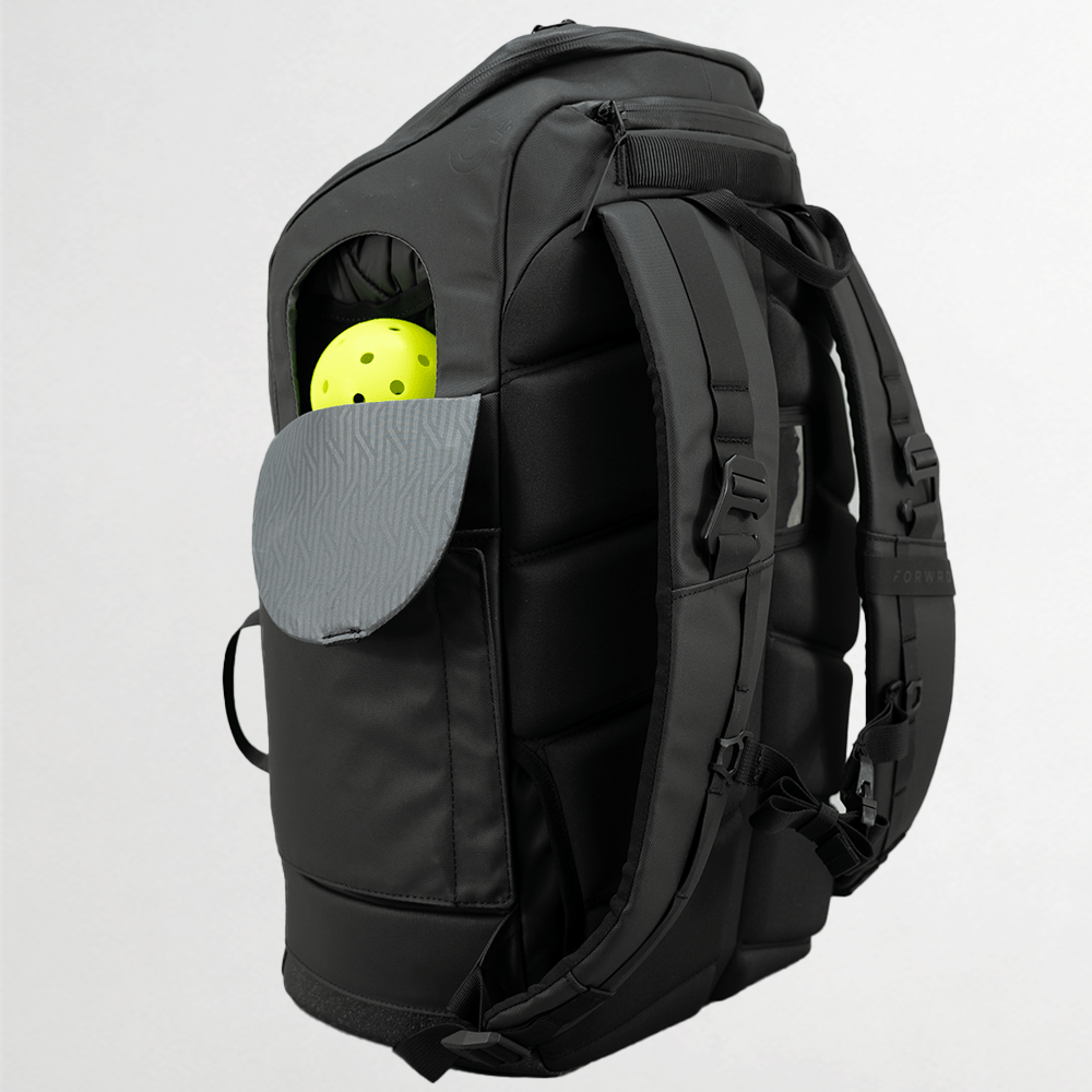 Black backpack with a yellow ball in an open compartment on a light gray background