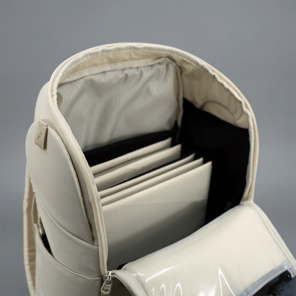 Beige backpack with open compartments on a gray background