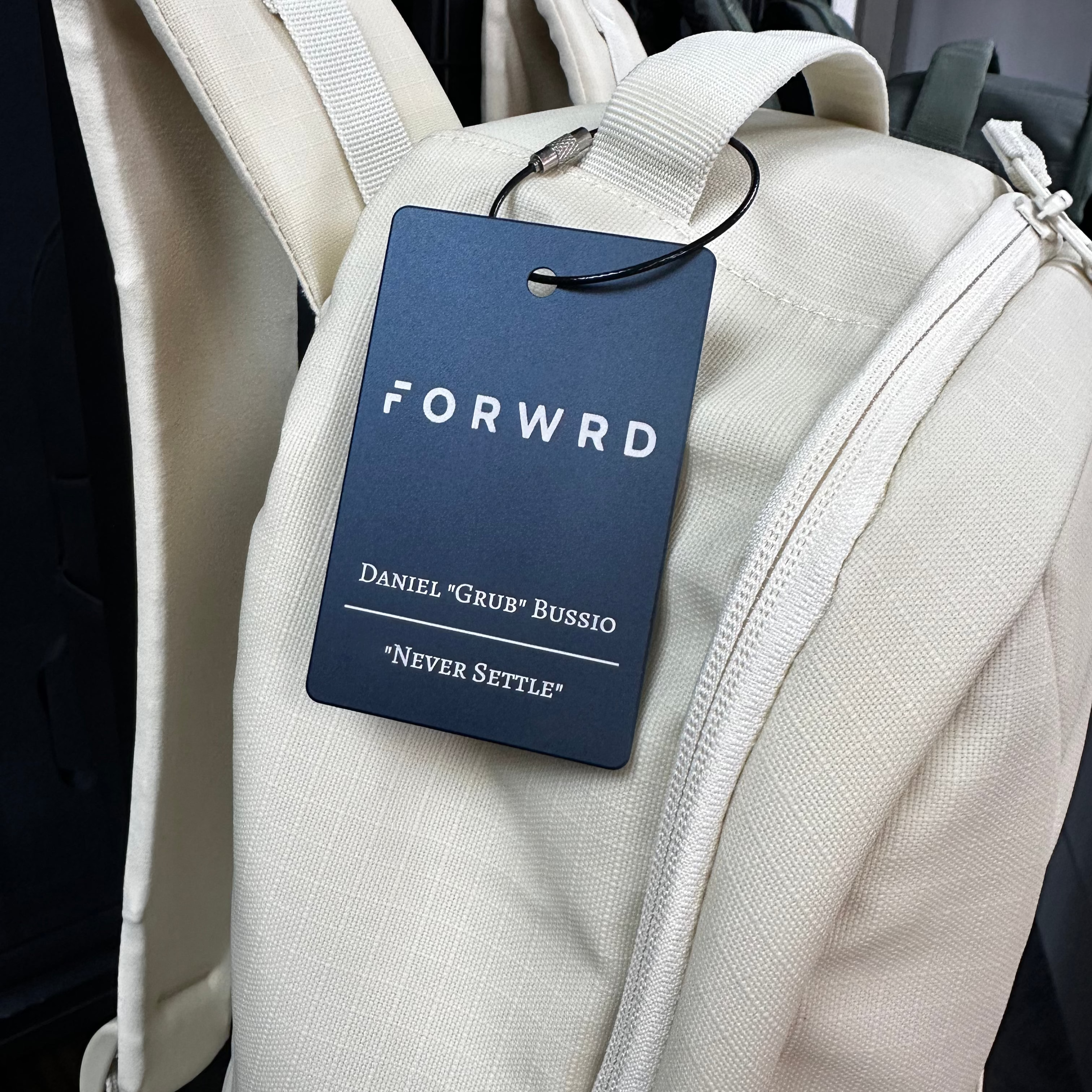 White backpack with a blue 'FORWRD' tag on a dark background
