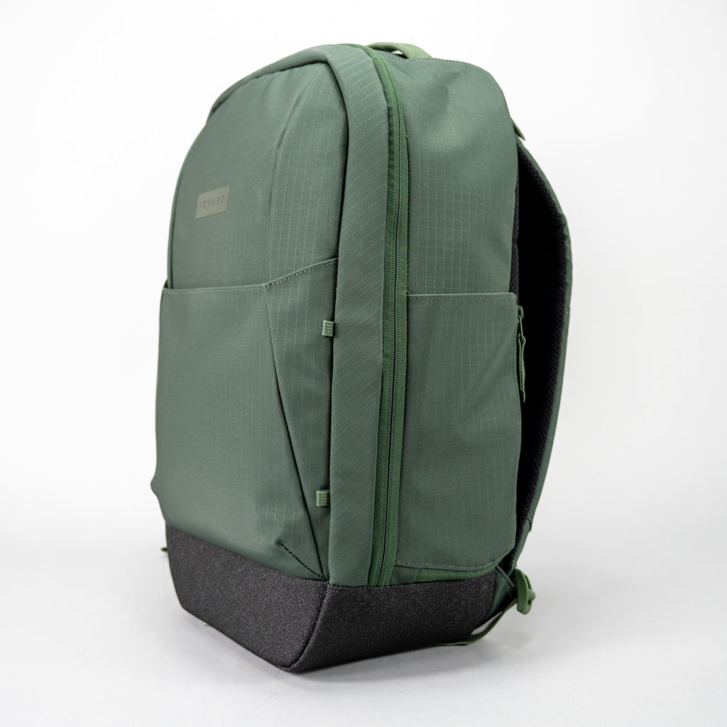 Side-angle view of the green FORWRD Court Ranger pickleball backpack, showcasing ripstop fabric construction, a side water bottle pocket, and a reinforced black base for durable on‑court gear storage.
