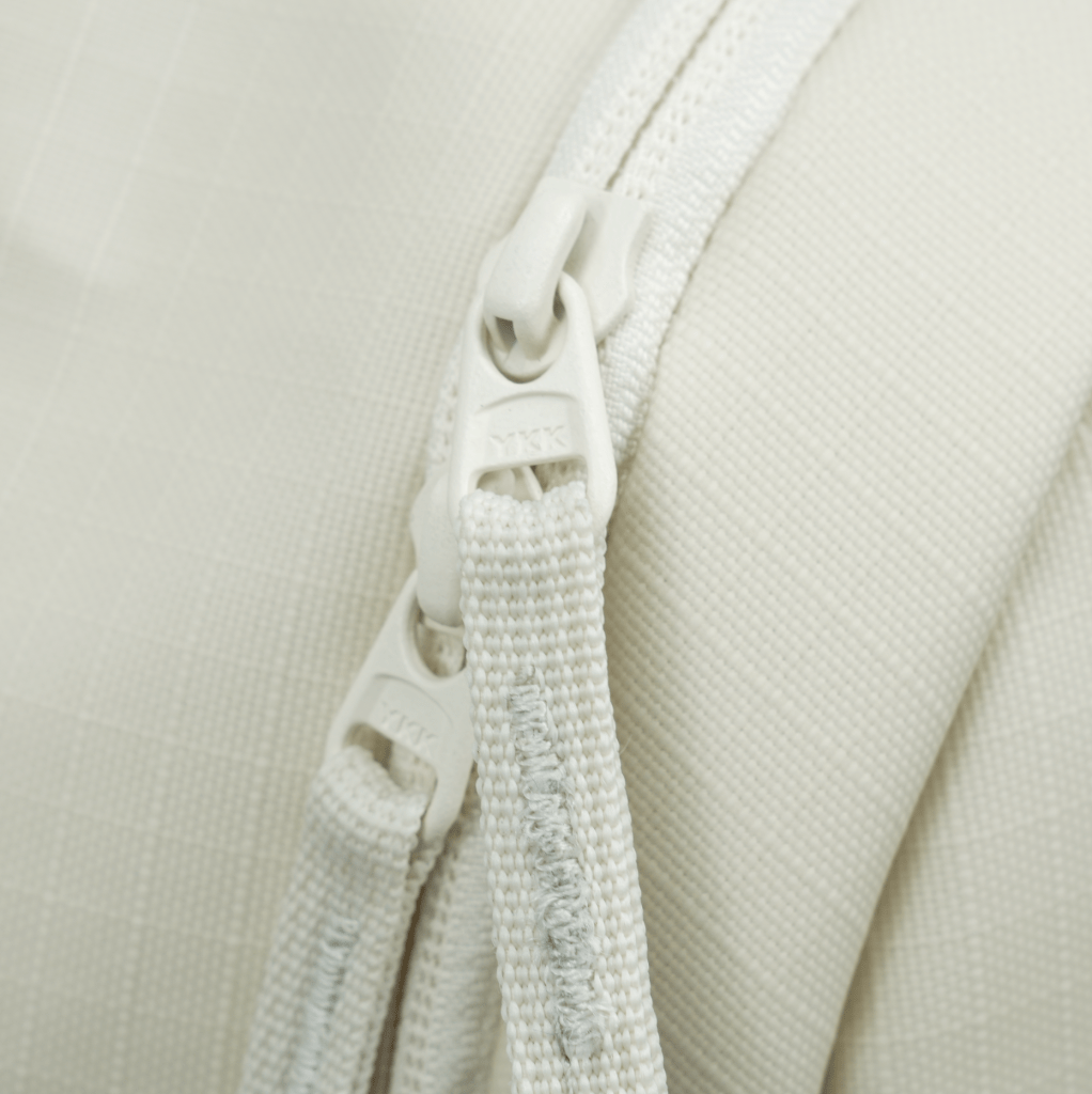 Close-up of a white zipper on a beige fabric background