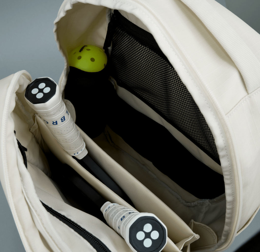 Close-up of a beige badminton bag with two rackets and a yellow shuttlecock.