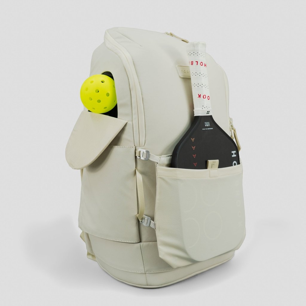 Beige backpack with a pickleball paddle and ball on a white background