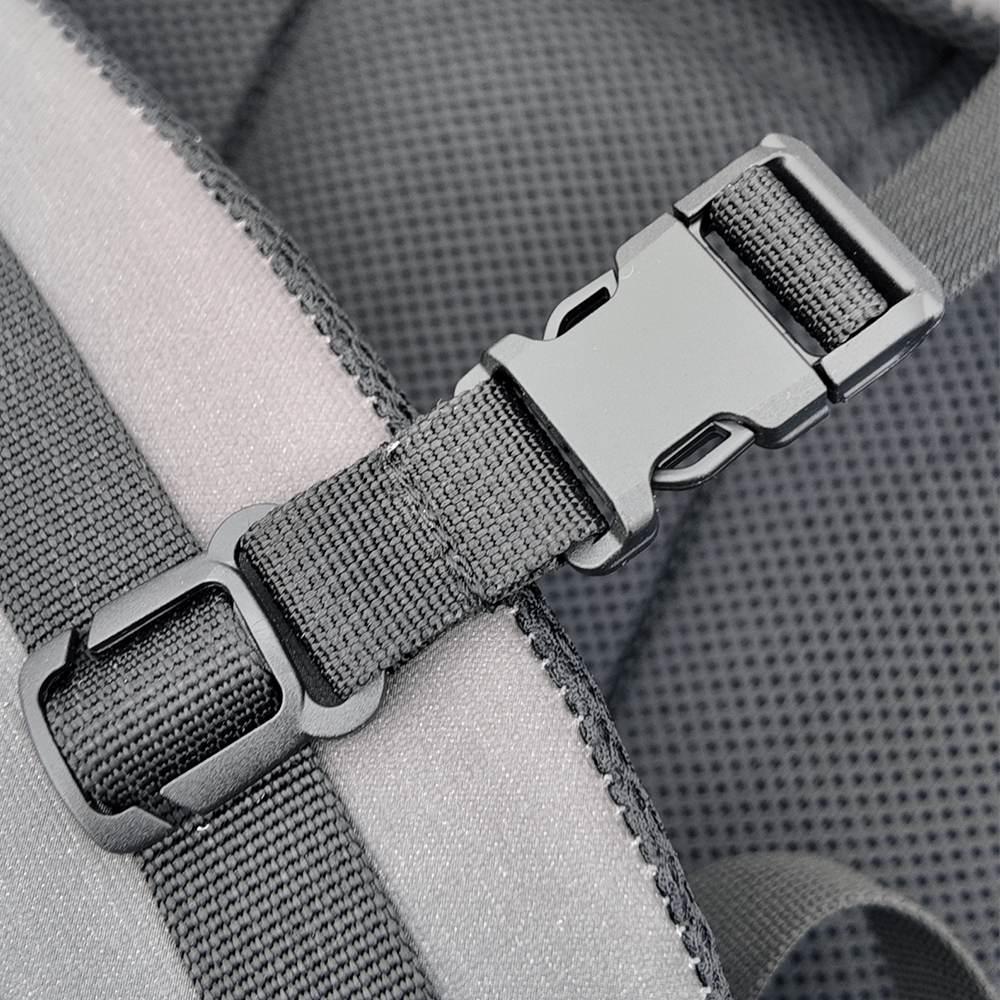 Close-up of a gray backpack strap with a metal buckle on a textured gray background.
