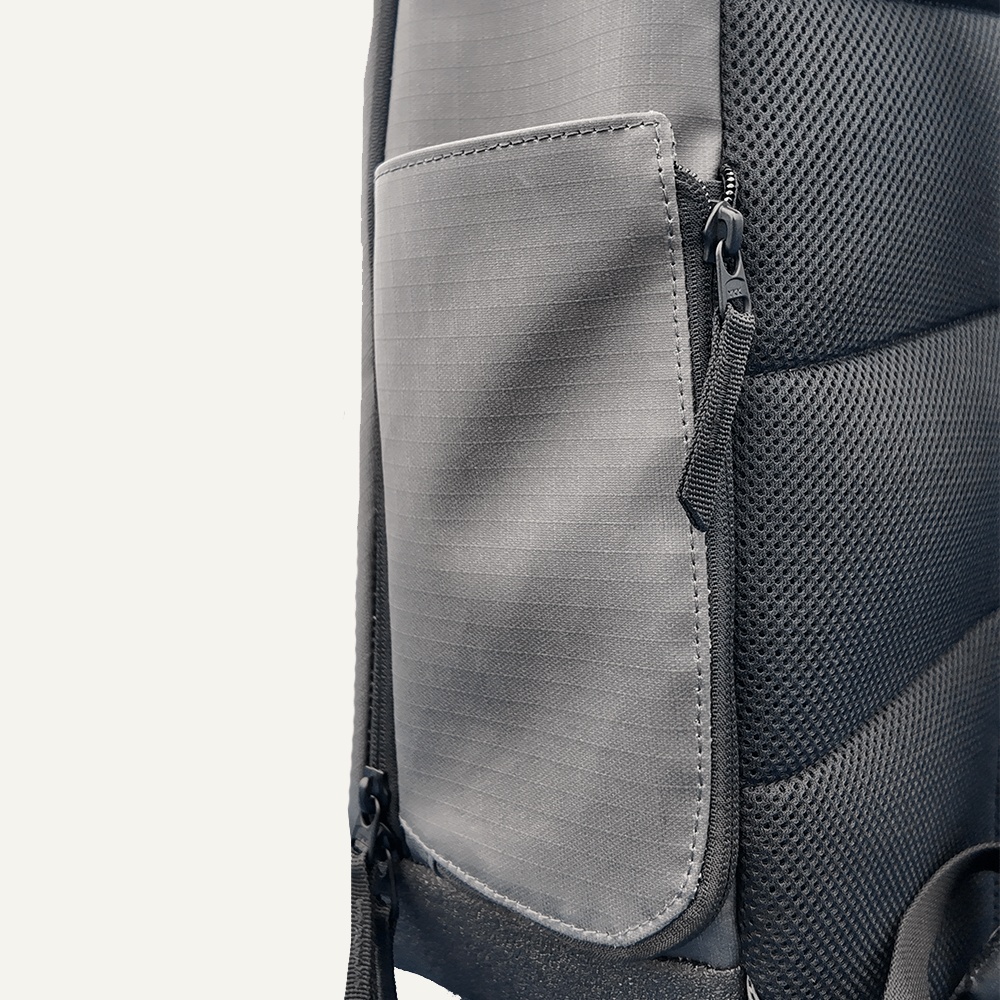 Close-up of a gray backpack with a zipper pocket on a light gray background