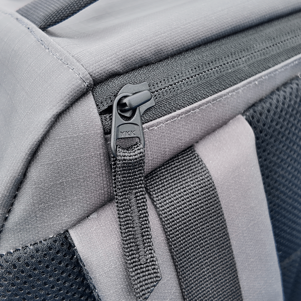 Close-up of a gray backpack with a zipper and mesh details
