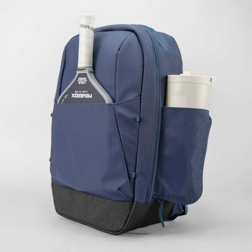 Blue backpack with tennis racket and cup on a light gray background