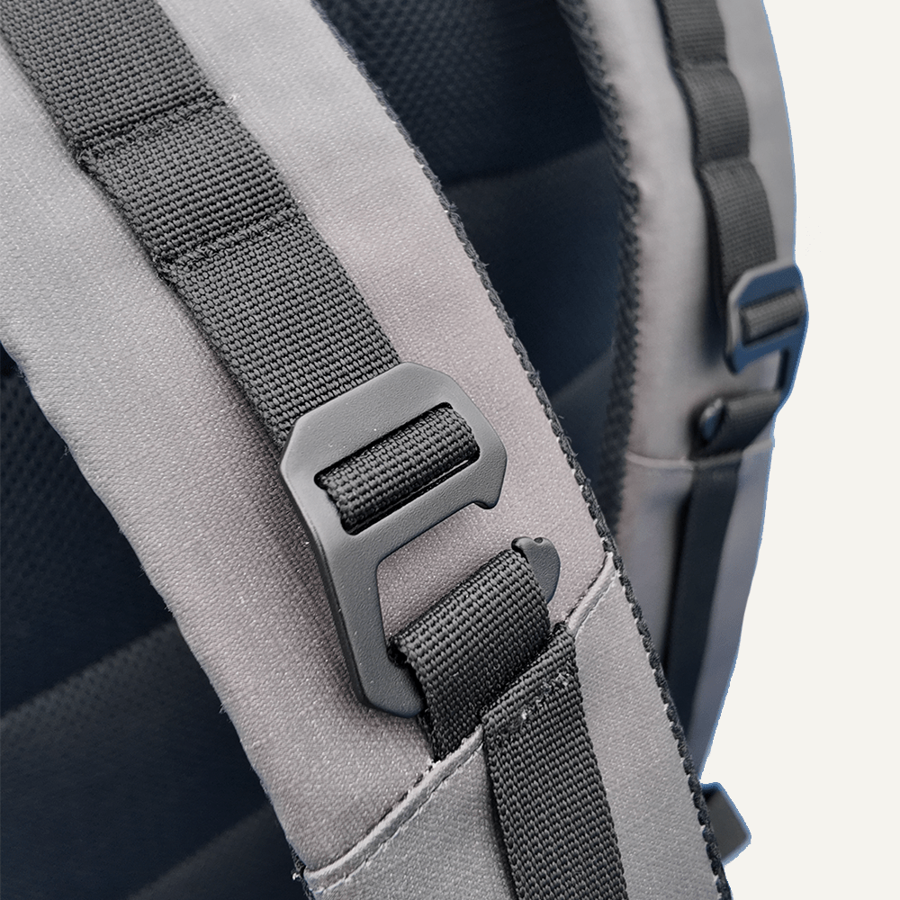 Close-up of a backpack strap with a buckle on a light gray background