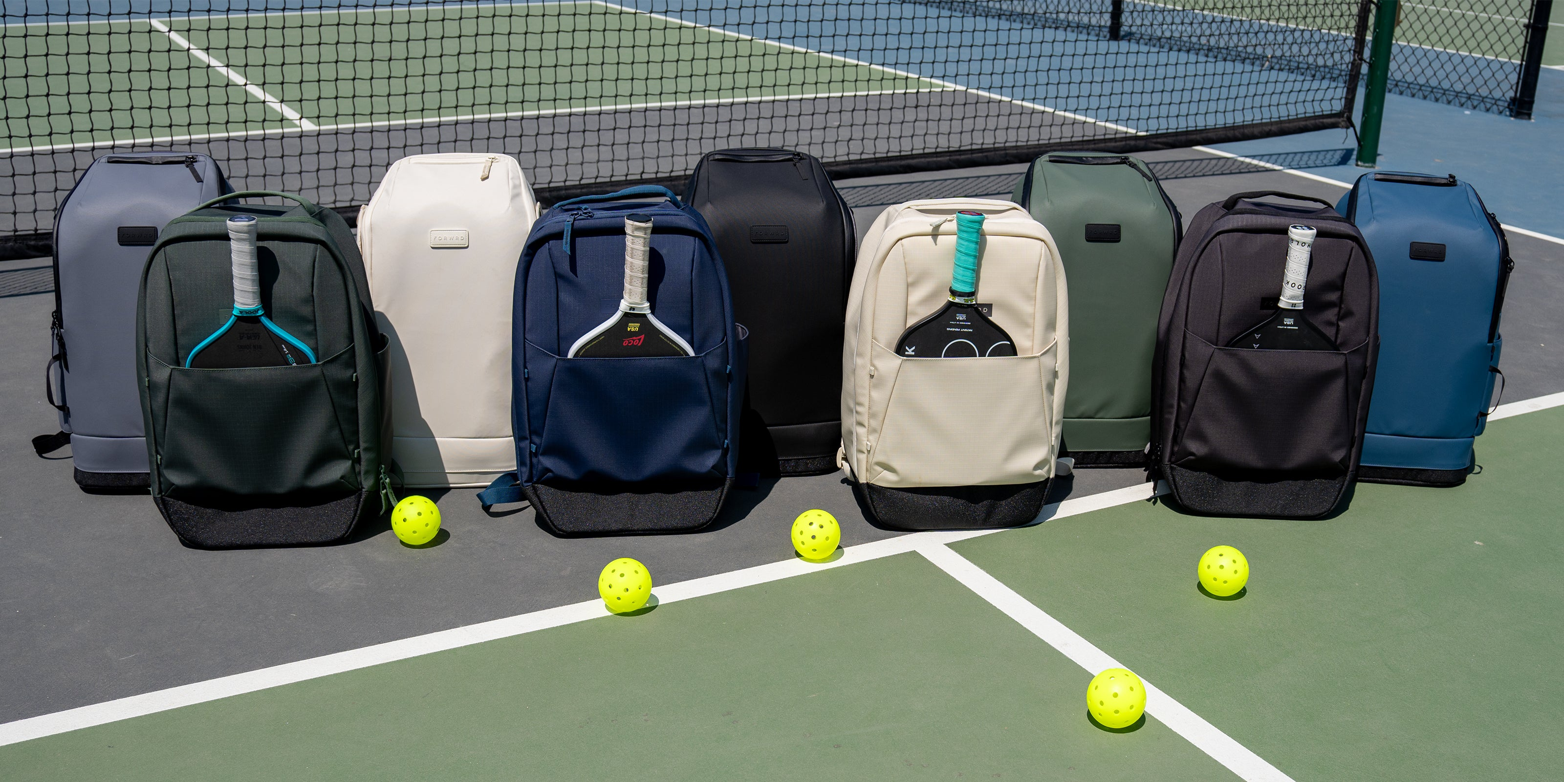 forwrd pickleball bags lined up in various colors on a pickleball court with pickleballs 
