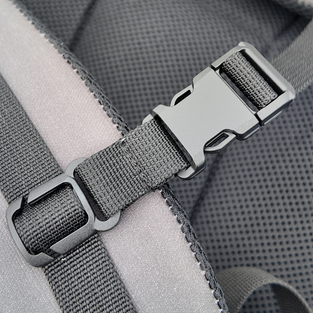 Close-up of a plastic buckle fastening a black strap on a gray fabric surface.