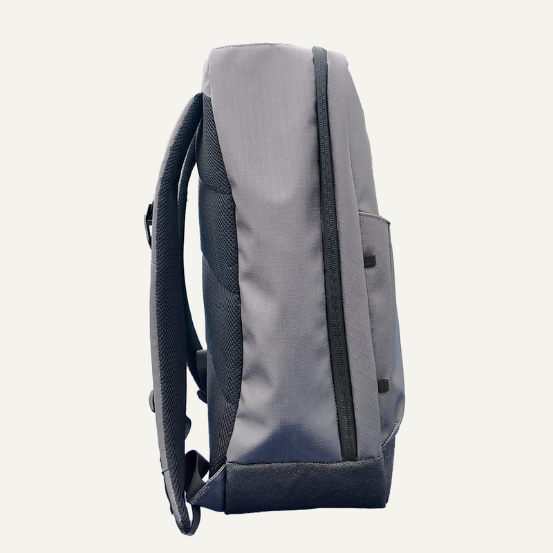 Side view of a grey backpack with a front pocket and adjustable straps.