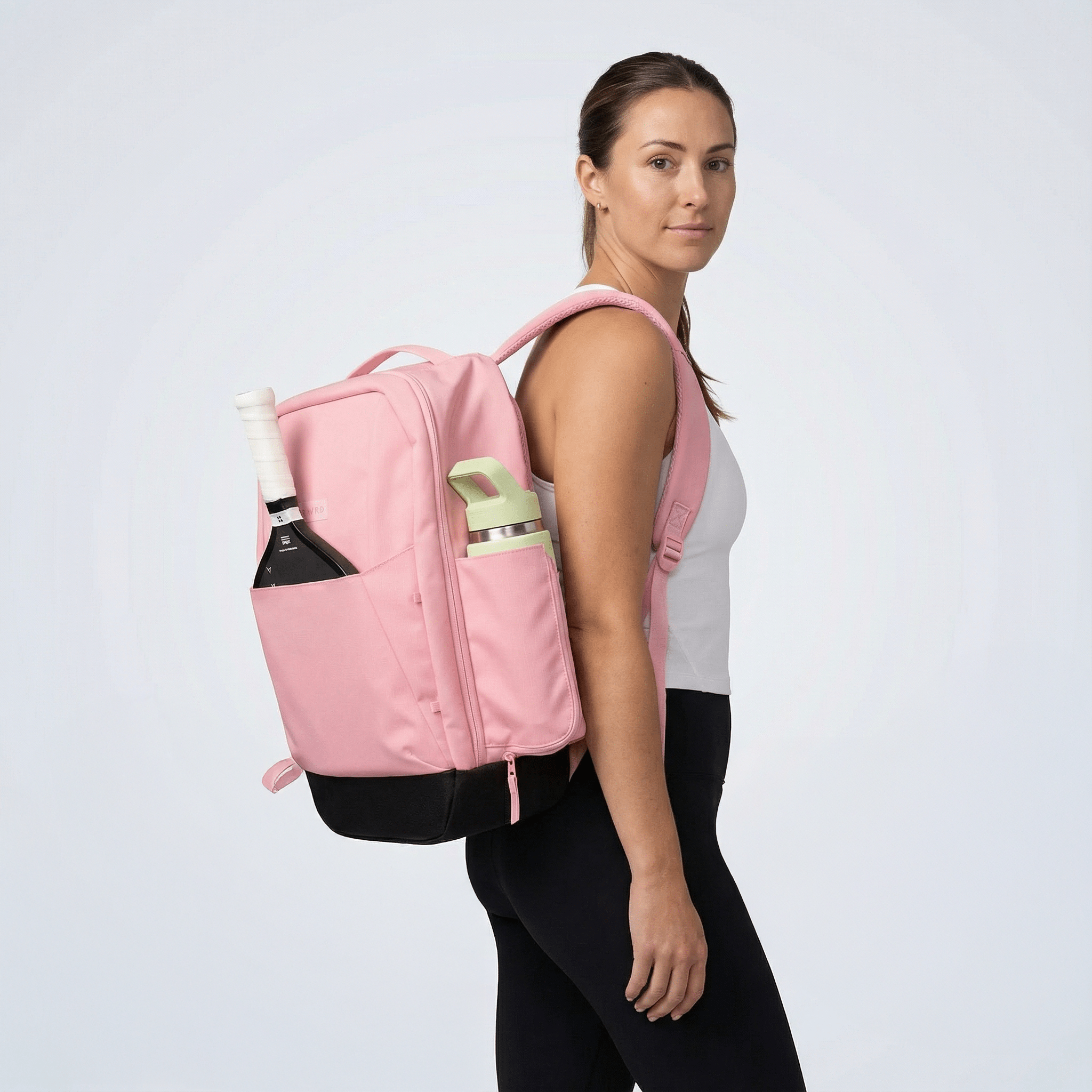 Person wearing a pink backpack with items on a light gray background